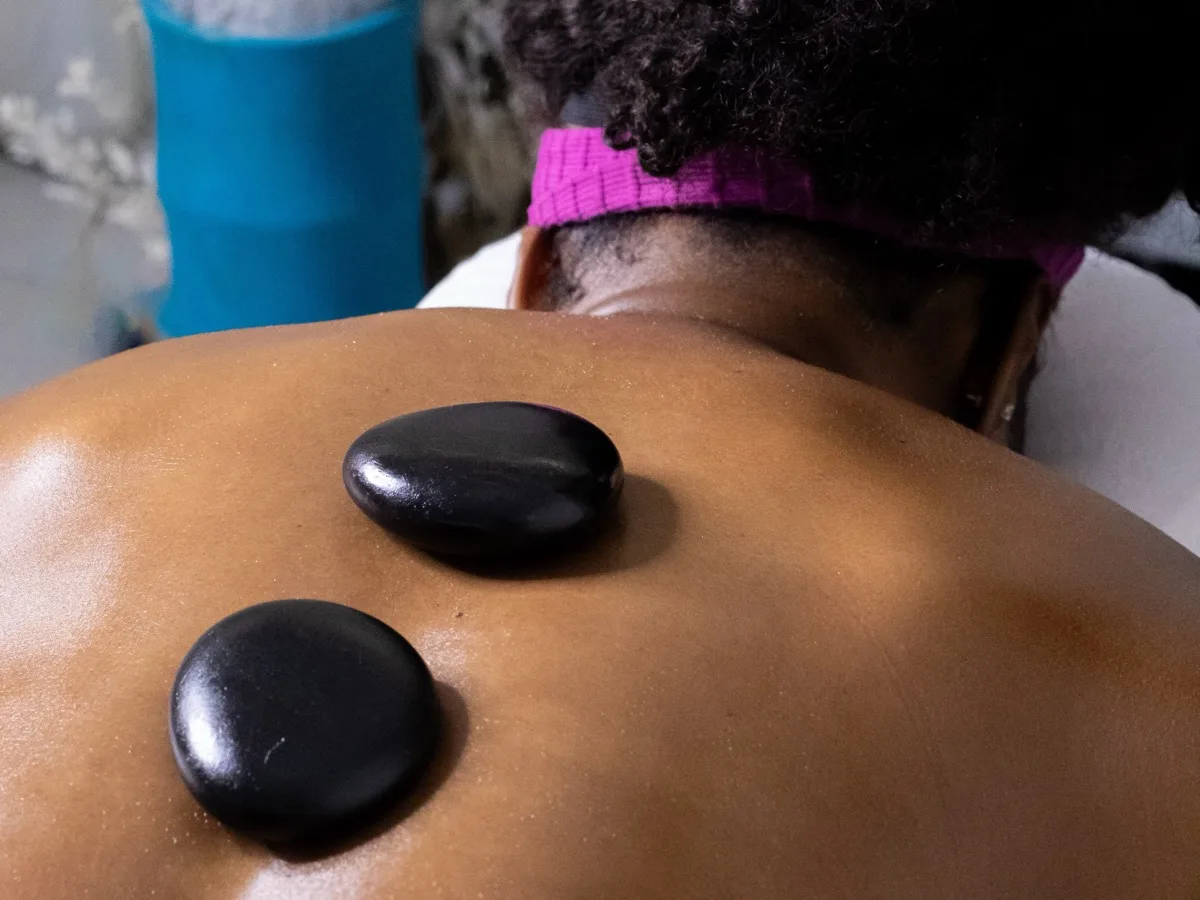 Hot stone massage at KiWest Spa Barbados - heated volcanic stones placed on client's back for deep muscle relaxation